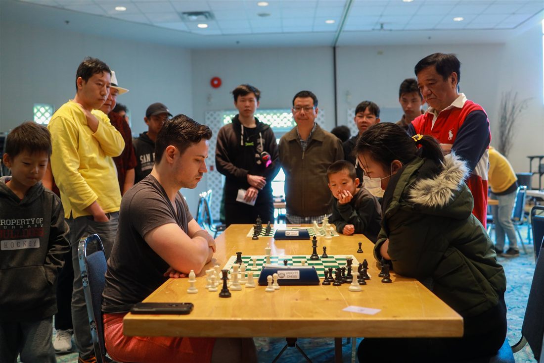 A crowd gathered around a table watching an intense game