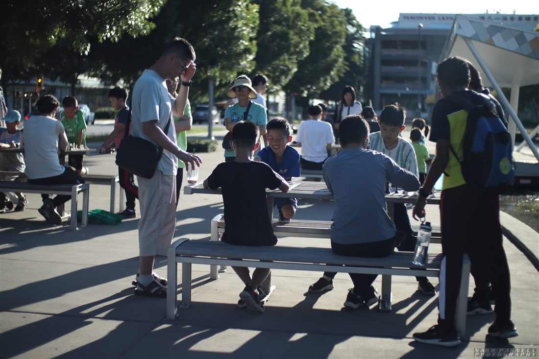 Kids playing chess together outdoors at a community event