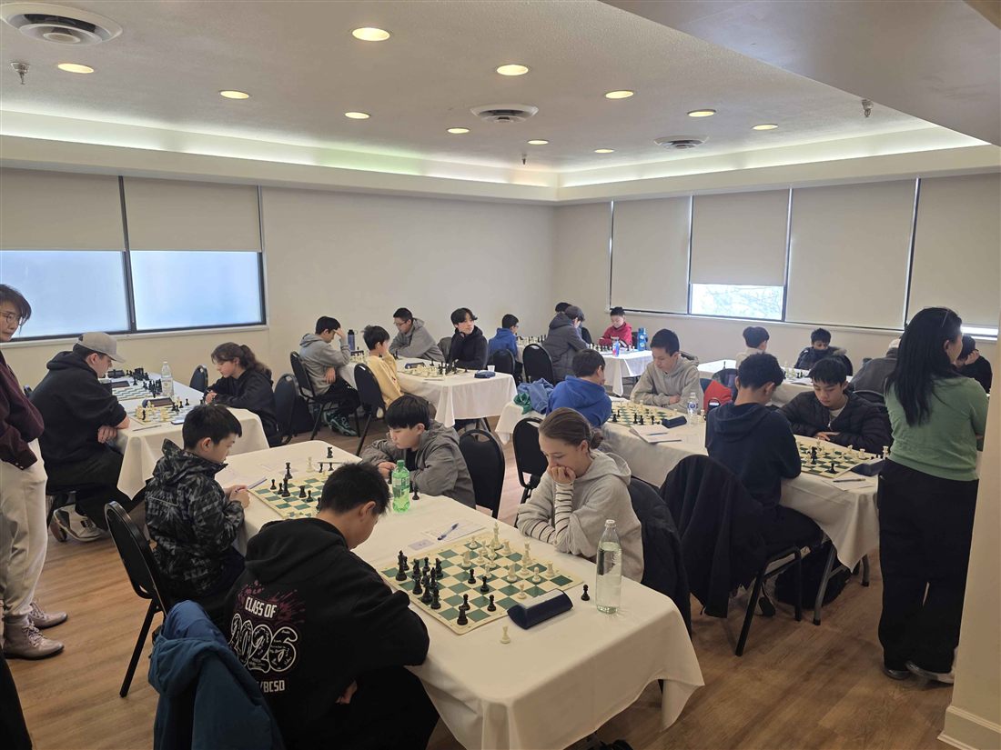 Players seated at rows of boards during a tournament round